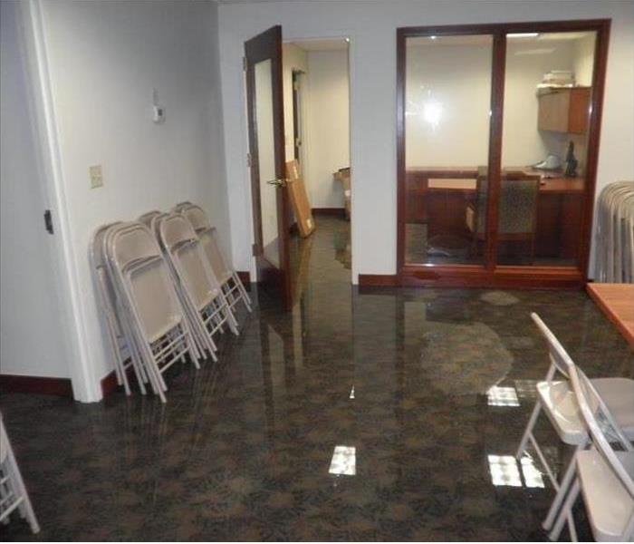 water reflecting ceiling lights in a flooded office area, chairs stacked on side